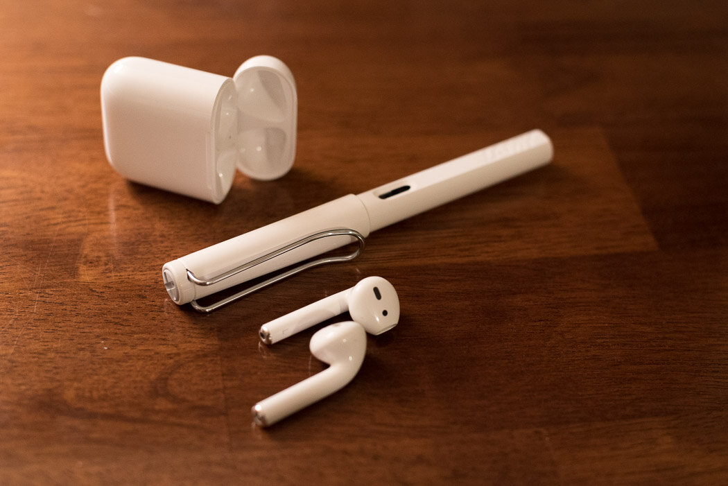 Open Apple AirPods case and Lamy Safari fountain pen on a desk