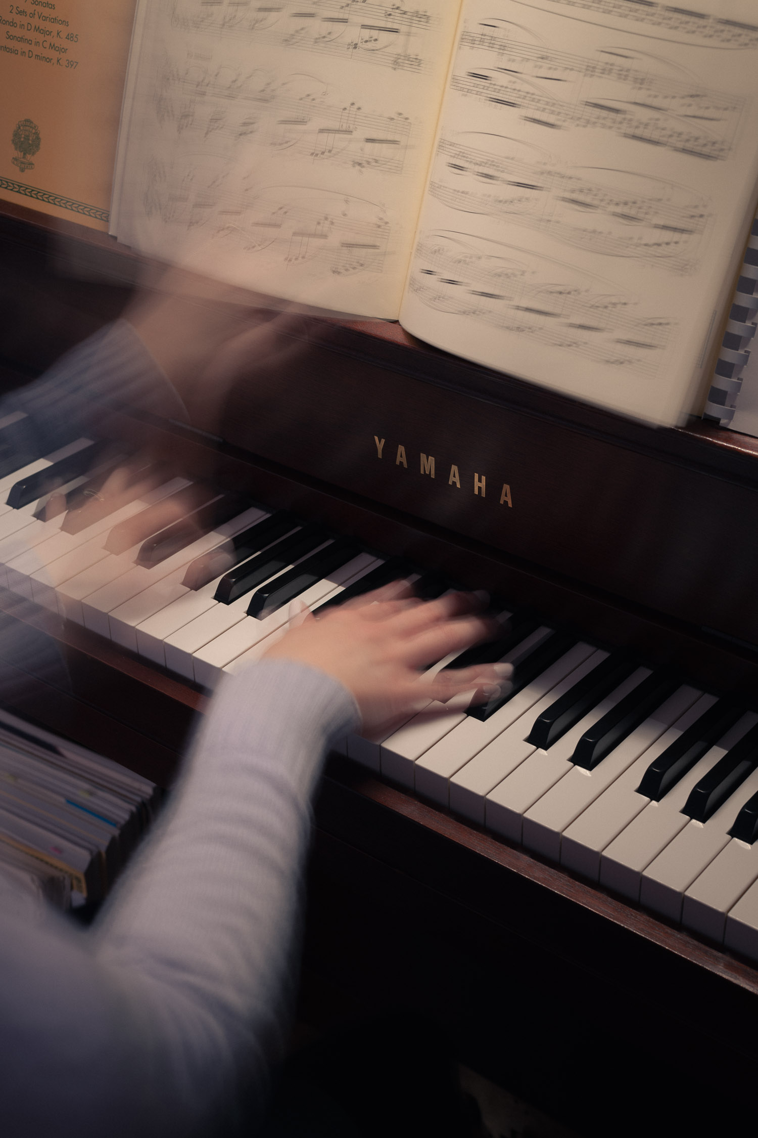 Hands at the piano playing Clair de Lune and turning a page with blurred motion