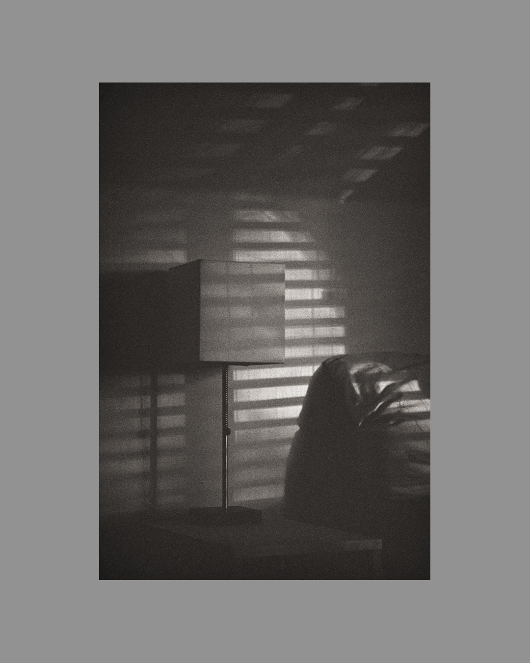 Film photograph showing lamp beside a bed with light filtering in through the blinds